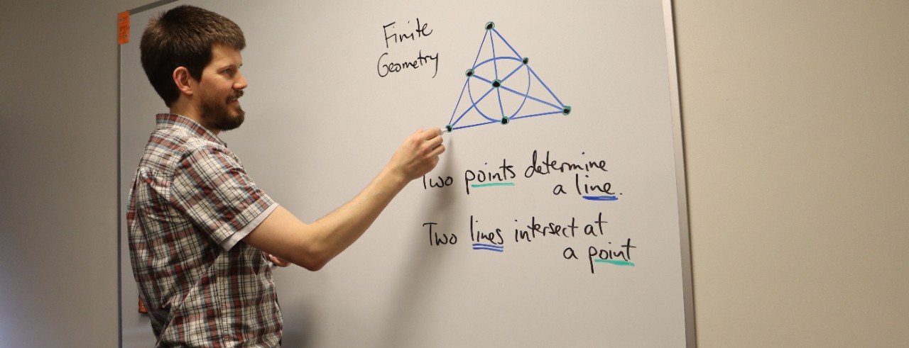 Professor writing mathematical diagram on a white board